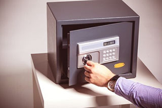 Someone with a black watch and purple sleeves opening a safe using a key