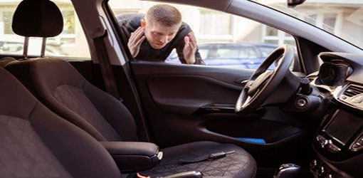 A man with a black shirt looking at a key left behind inside the car