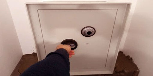 Someone with black sleeves opening a white safe